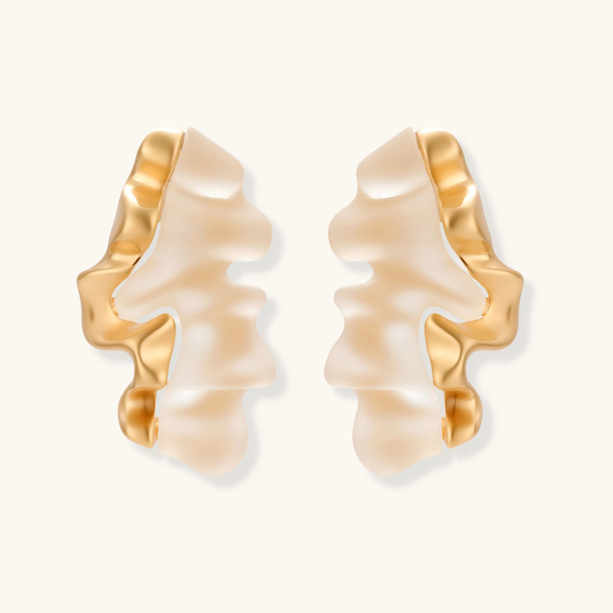 Sculptural gold-edged earrings with translucent resin centers in flowing wave shapes on neutral background.