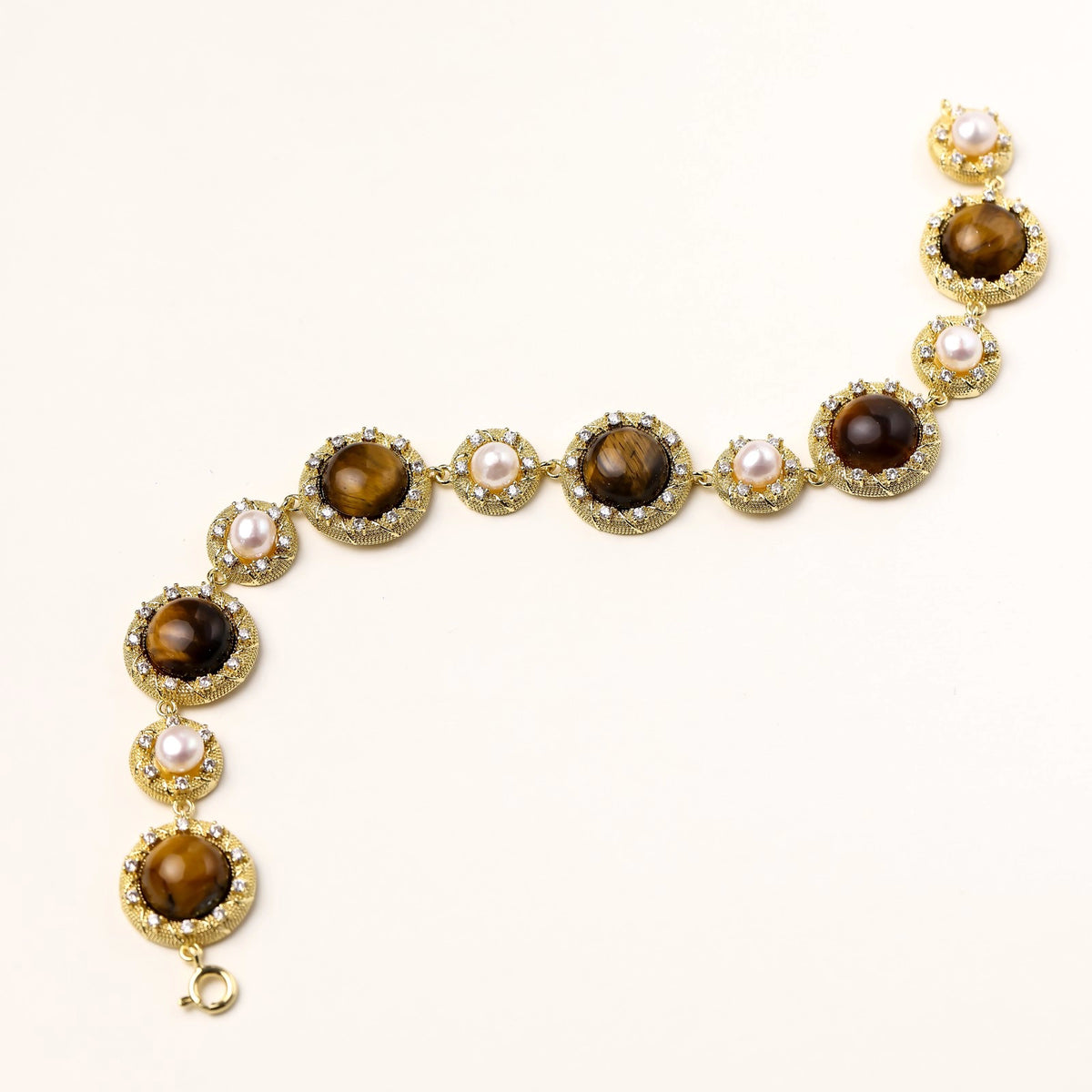 Gold-plated link bracelet with alternating brown tiger's eye stones and white freshwater pearls in ornate bezels.