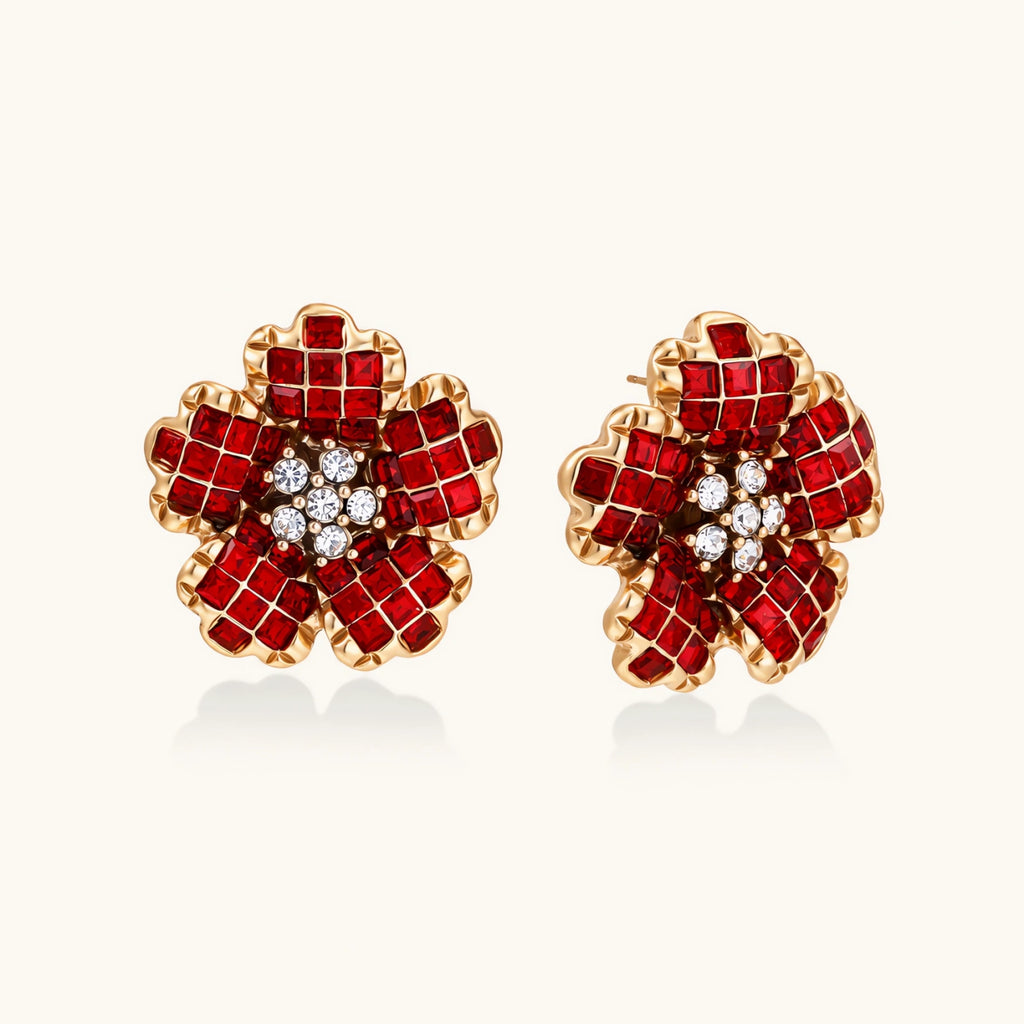 Gold-plated flower studs with burgundy square crystals in petal mosaic and clear center stones on beige background.
