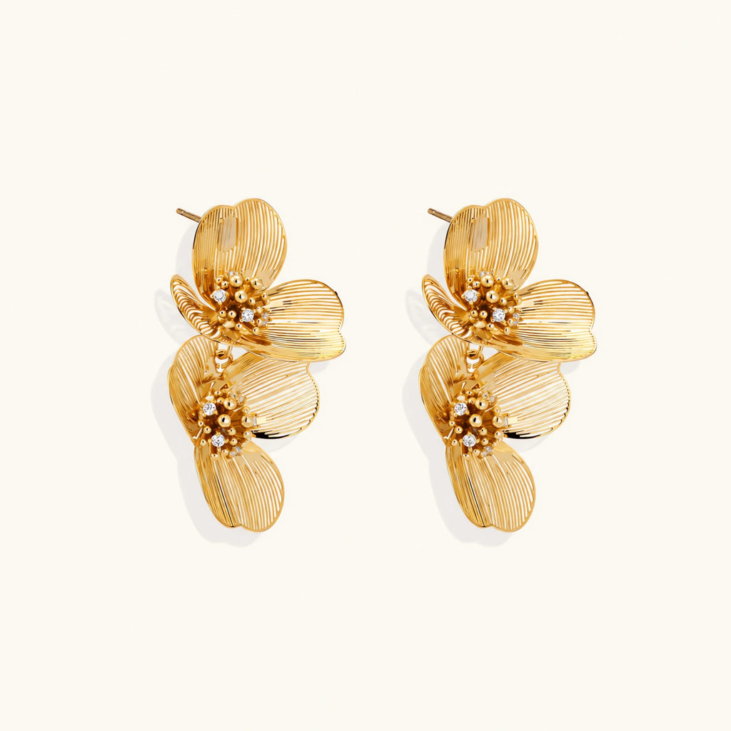 Pair of gold-plated double flower earrings with textured petals and crystal centers on cream background.