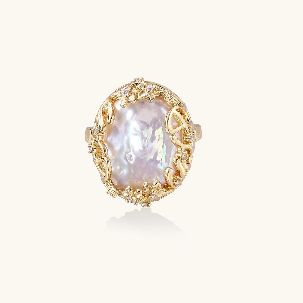 Gold filigree crown ring cradling an iridescent baroque freshwater pearl with crystal accents on white background