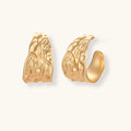 Gold-toned hoop earrings with organic ripple texture and molten-like surface design on neutral background.