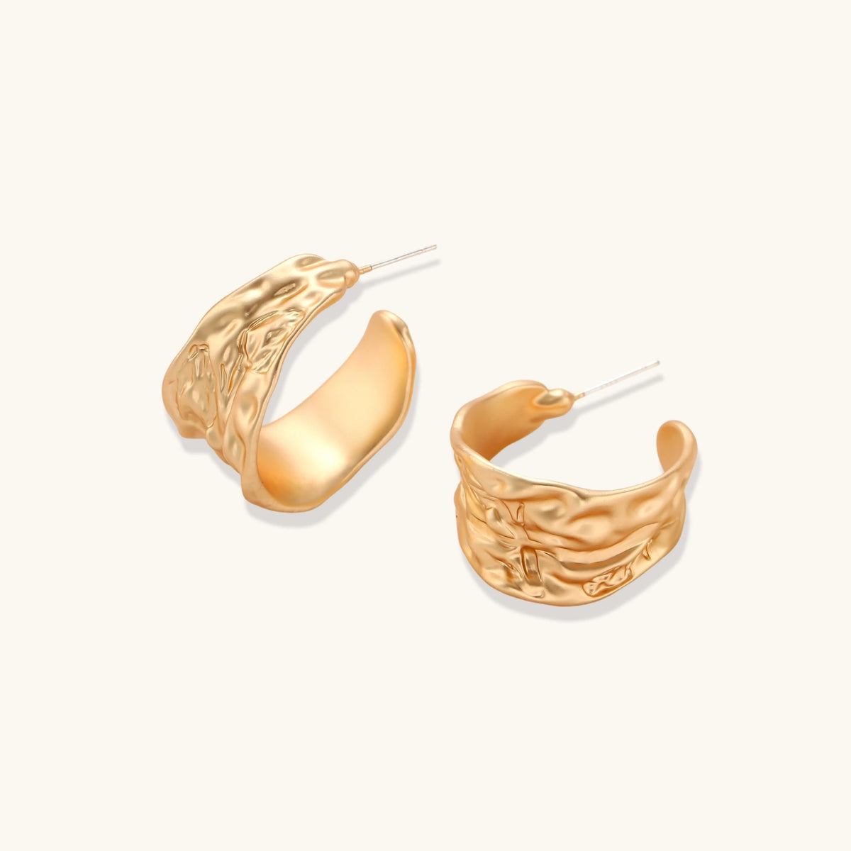 Gold-toned hoop earrings with organic ripple texture and molten-like surface design on neutral background.