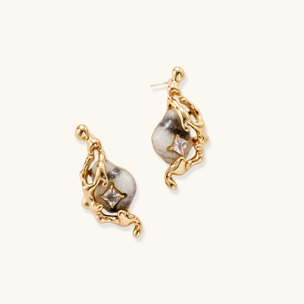 Gold-toned dangle earrings with marbled resin stones and flowing serpentine chain design on neutral background
